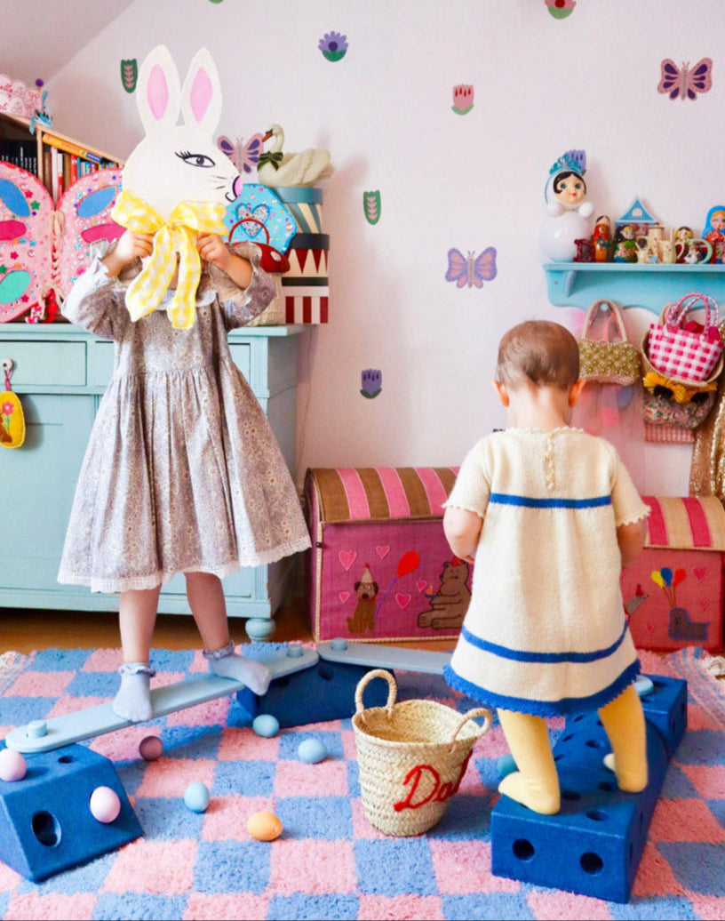 Two children playing in a colorful children's room with butterfly decals, toys and decorations.