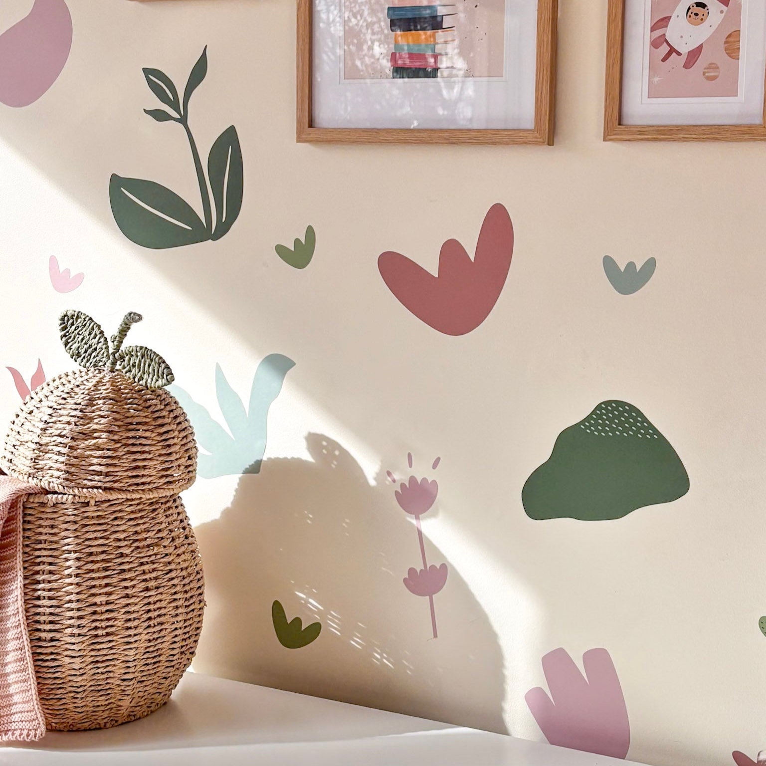 Children's room with framed artwork and decorative wall stickers on a light-colored wall.