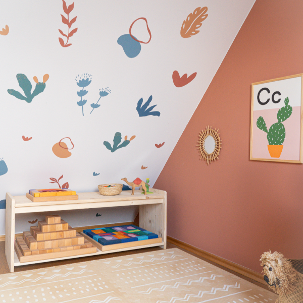 Children's playroom with toys on a shelf, colorful wall decals, and a framed picture.