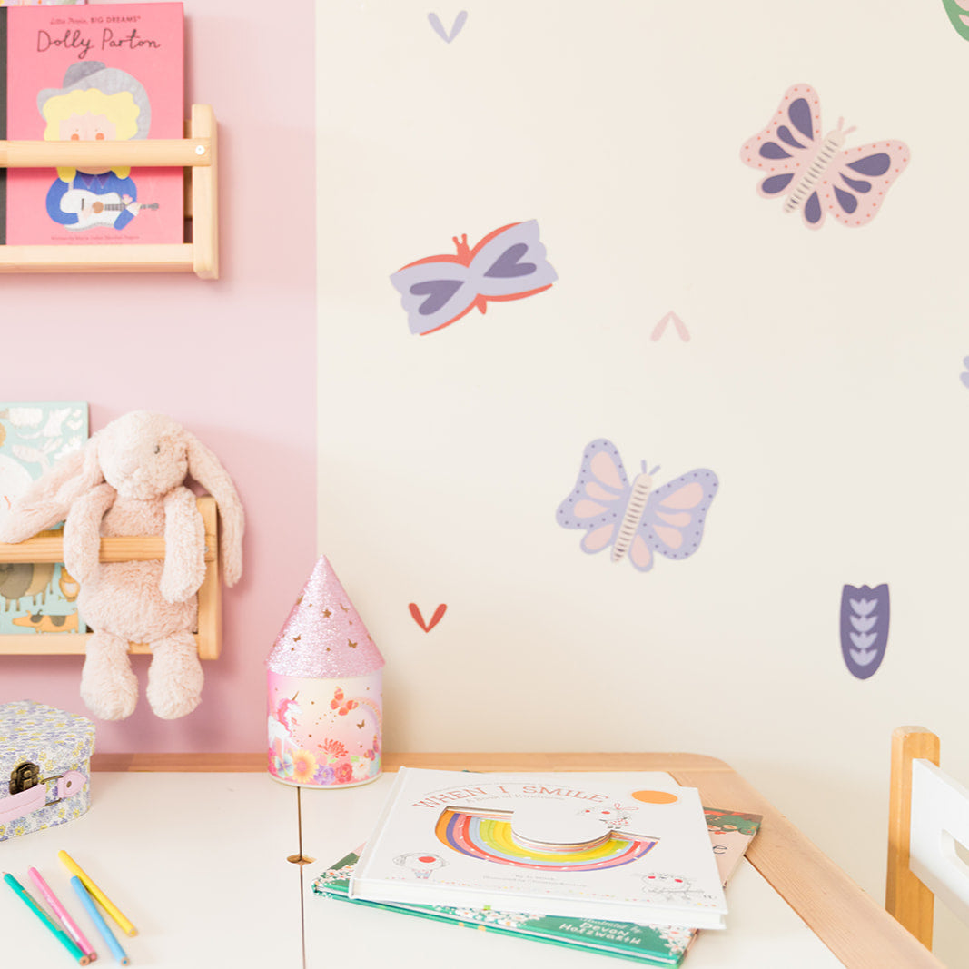 Children's room with books, toys, and butterfly wall decals on a pink wall.