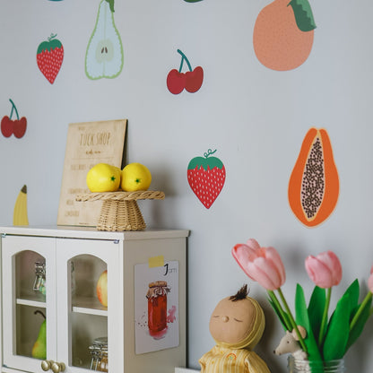 Children's play area with fruit-themed wall decals, a doll, and flowers.
